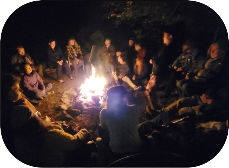 people sitting around an outdoor campfire